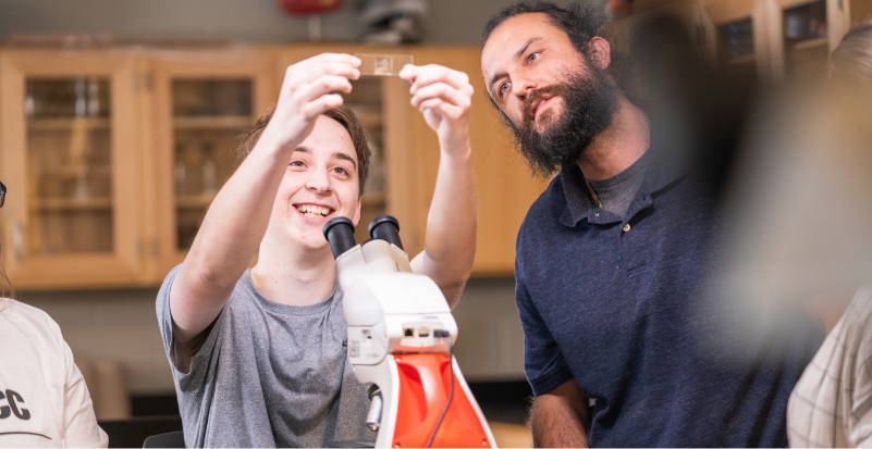 Two people looking at a microscope slide