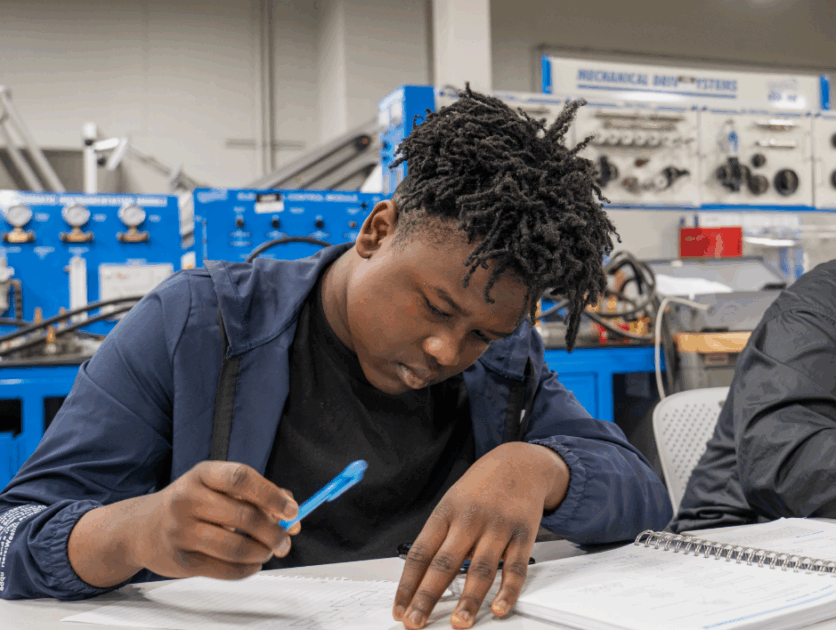 A student looking at a piece of paper and holding a pen.