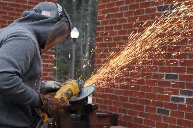A person wearing protective gear using an angle grinder