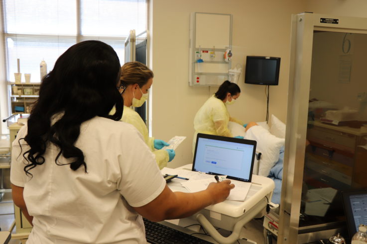 A woman standing in front of a monitor in a hospital room