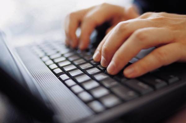 Closeup of hands typing on a laptop keyboard