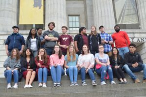 A group of students standing and seated on outside steps.