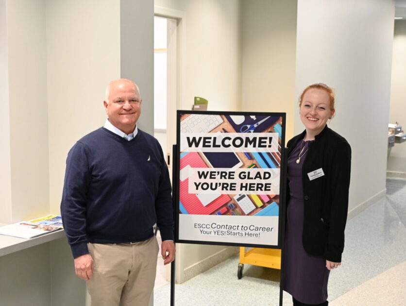 Rob McClaugherty and Hayleigh Bradbury standing beside a sign in a hallway
