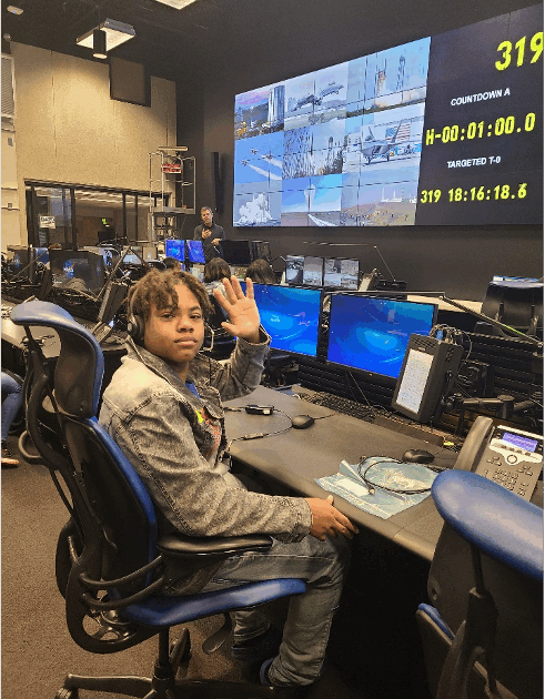 A man seated in a room with many computers and monitors set up.