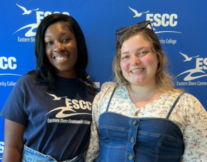Two students standing in front of a backdrop with the ESCC logo on it.
