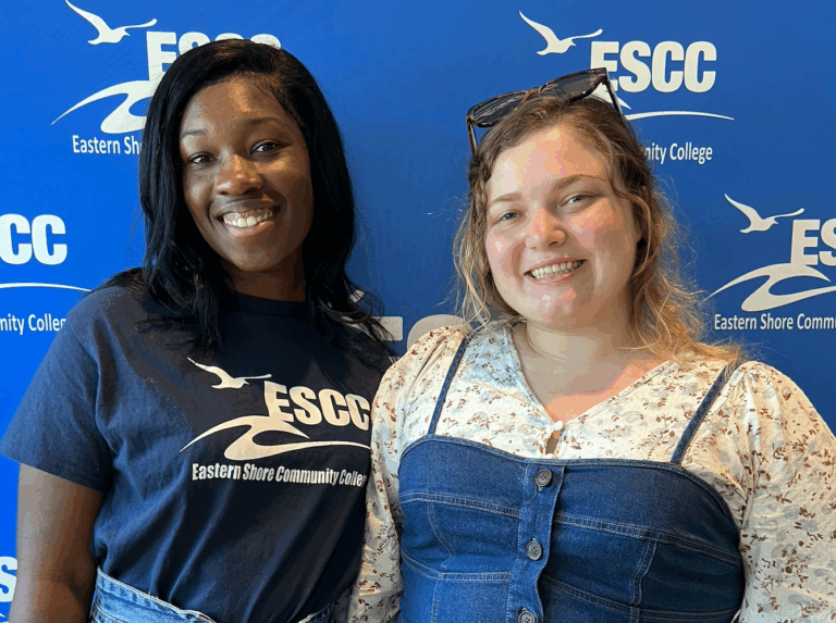 Two students standing in front of a backdrop with the ESCC logo on it.