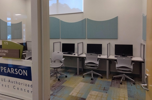 A row of computer stations with chairs in front of them.