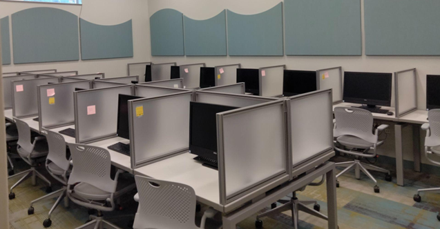 Rows of computer stations with chairs in front of them.