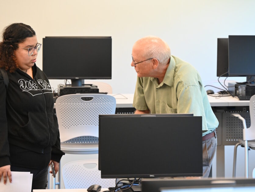 Two people standing among rows of computer workstations