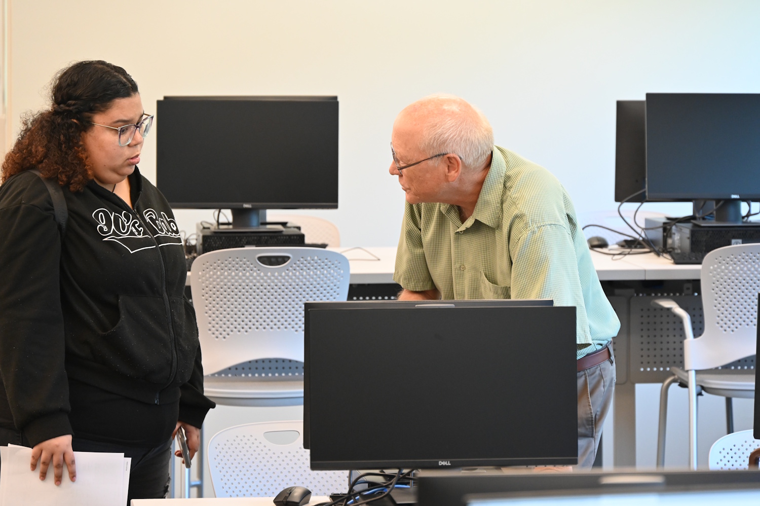 Two people standing among rows of computer workstations