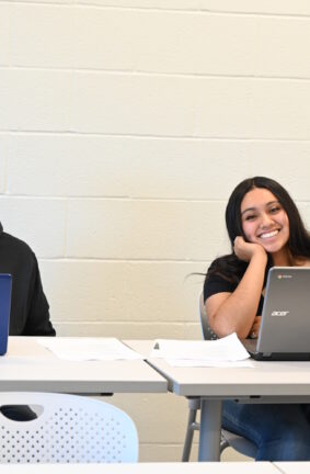 Two people seated at tables and using laptops