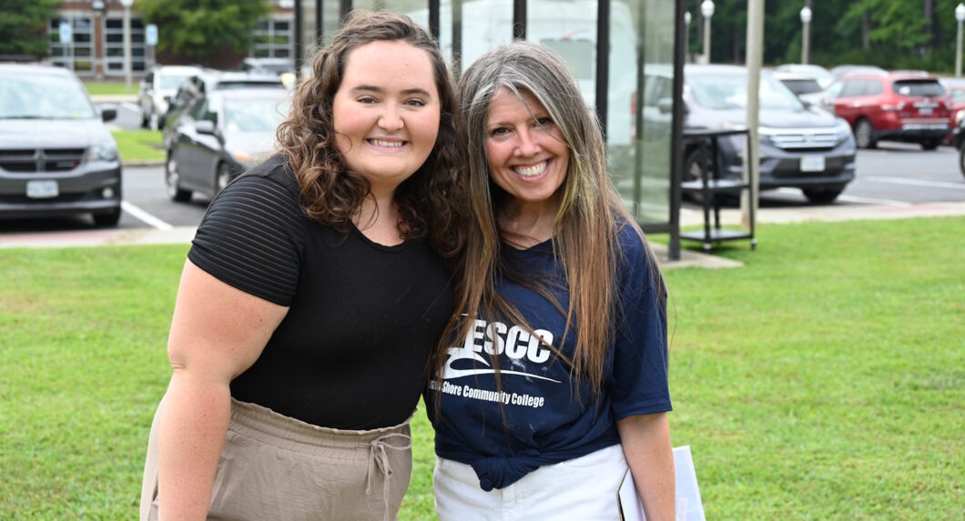 Two women standing outside with a parking lot behind them