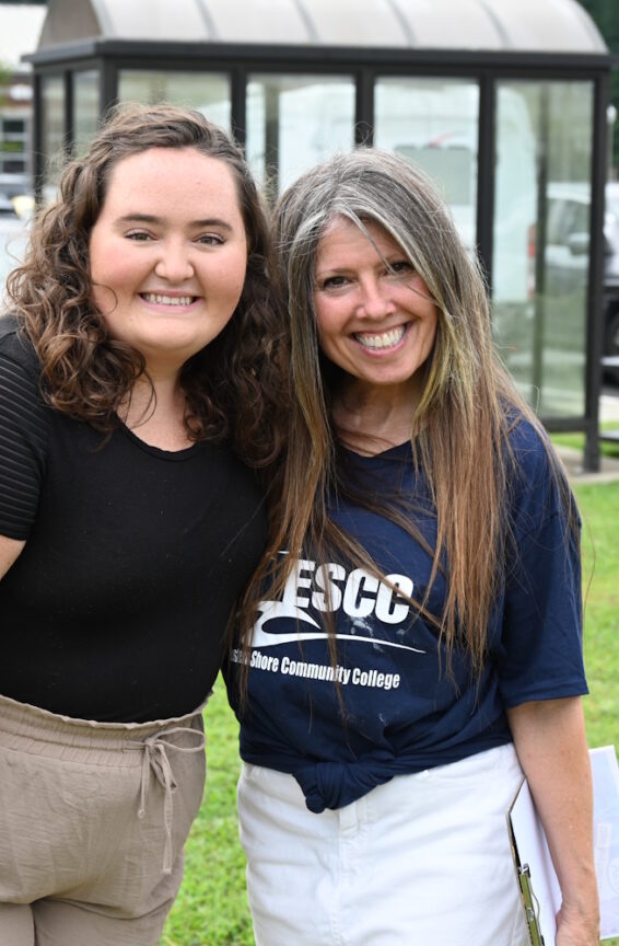 Two women standing outside with a parking lot behind them