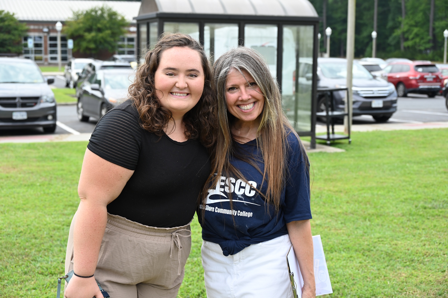 Two women standing outside with a parking lot behind them
