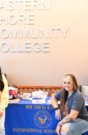 People standing in front of a table with a Phi Theta Kappa banner on it
