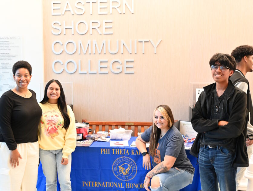 People standing in front of a table with a Phi Theta Kappa banner on it
