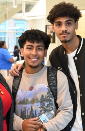 Three people standing in a hallway near a stairwell