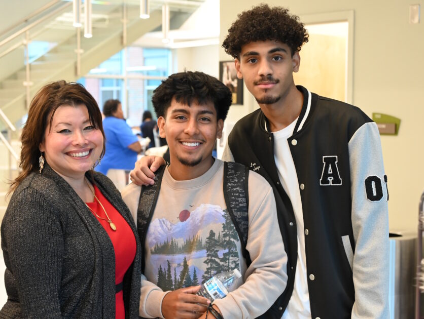 Three people standing in a hallway near a stairwell