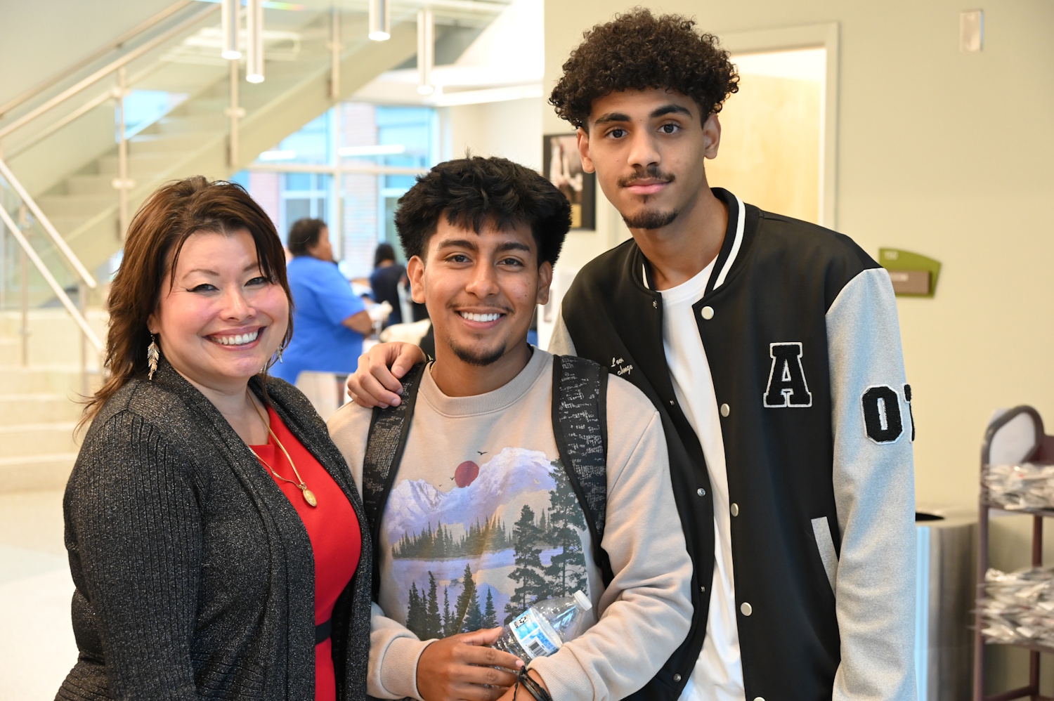 Three people standing in a hallway near a stairwell