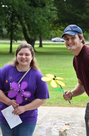 Three people standing outside holding artificial flowers