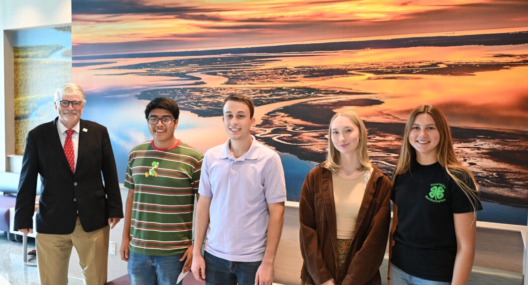 A group of people standing in front of a wall with a large mural on it.
