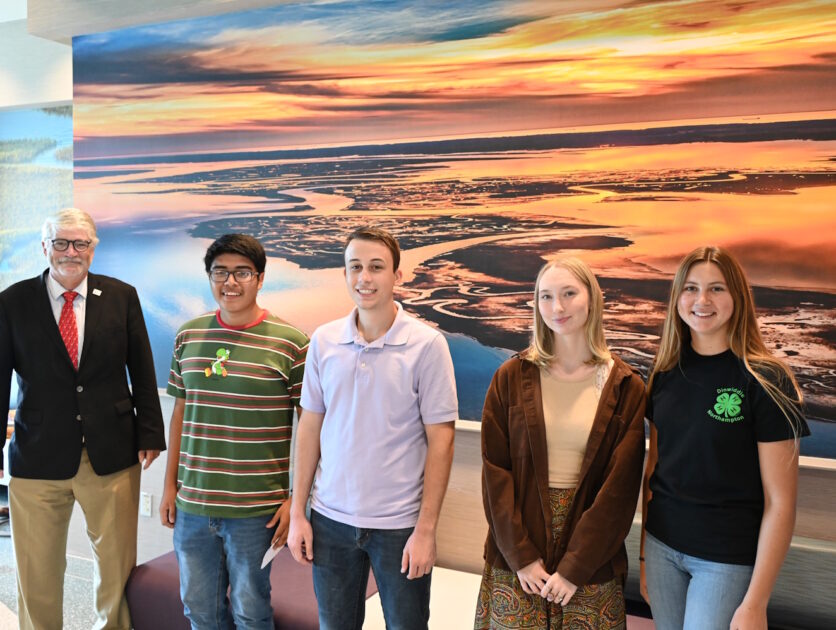 A group of people standing in front of a wall with a large mural on it.