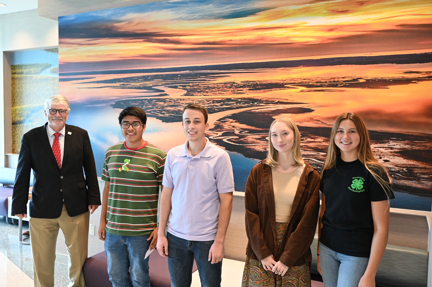 A group of people standing in front of a wall with a large mural on it.