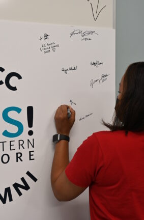 A woman writing on a posterboard with the Yes Eastern Shore logo on it.