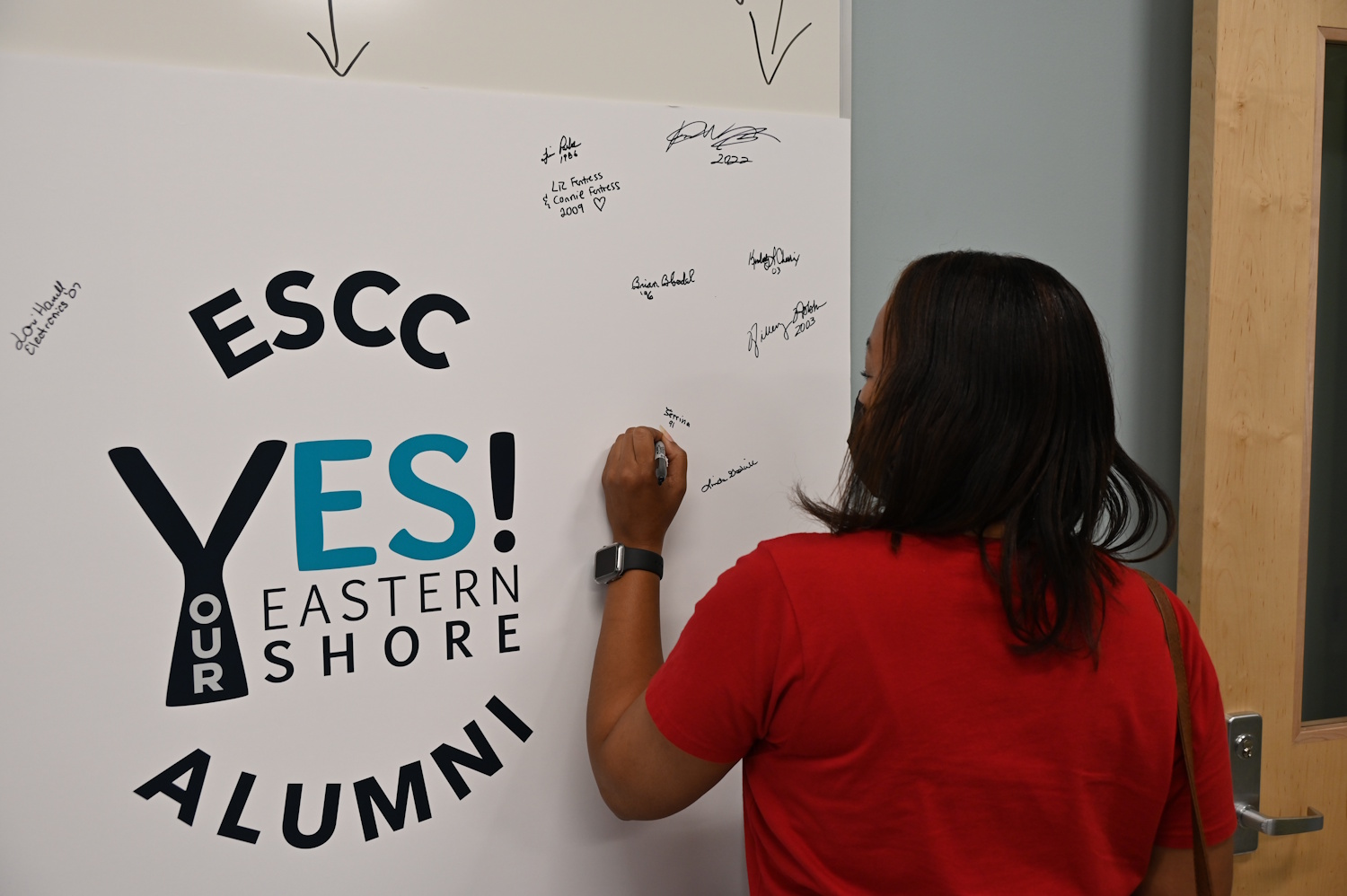 A woman writing on a posterboard with the Yes Eastern Shore logo on it.