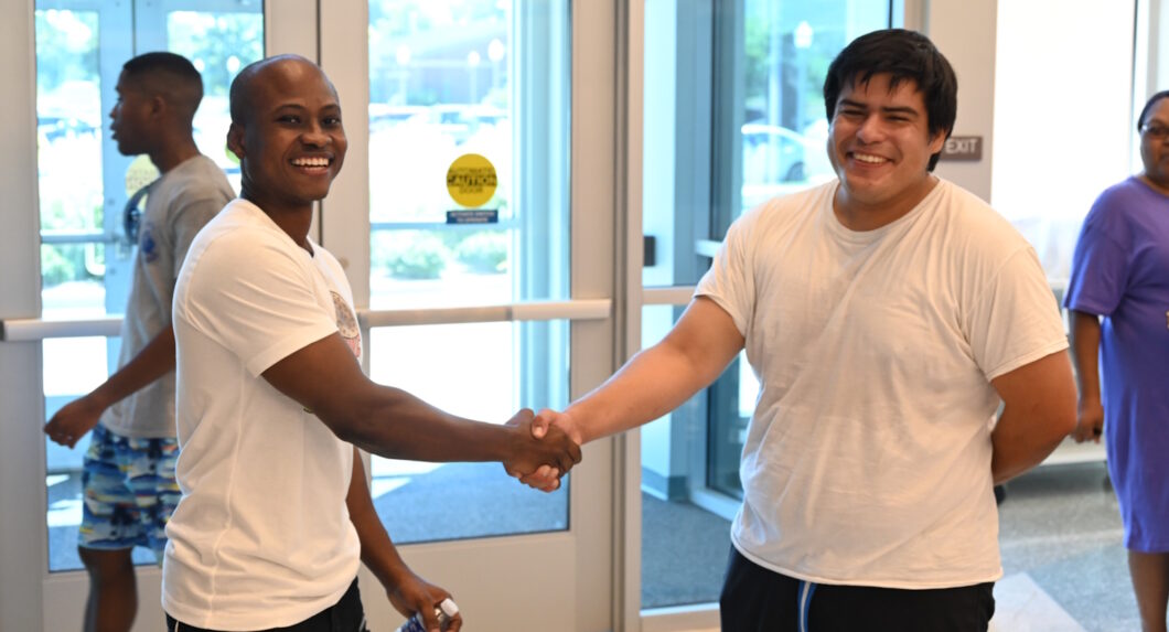Two men standing in a foyer shaking hands