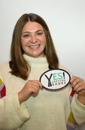 A woman holding up a Yes! Eastern Shore emblem