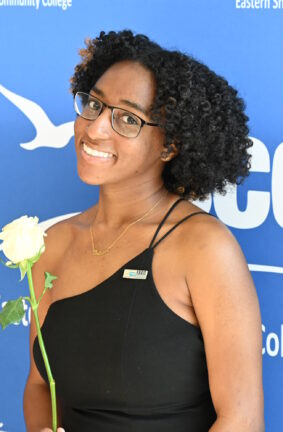 A woman standing in front of a wall displaying the ESCC logo