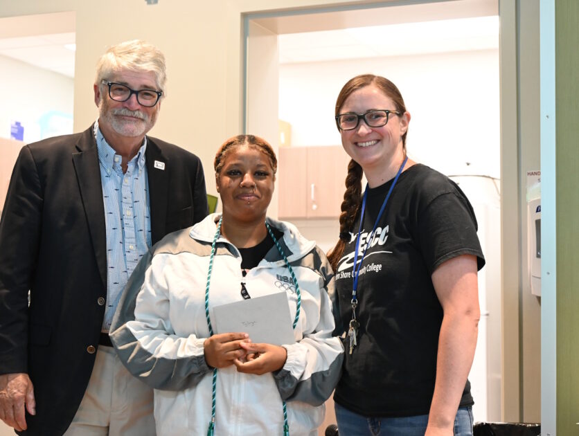 Three people standing in a hallway