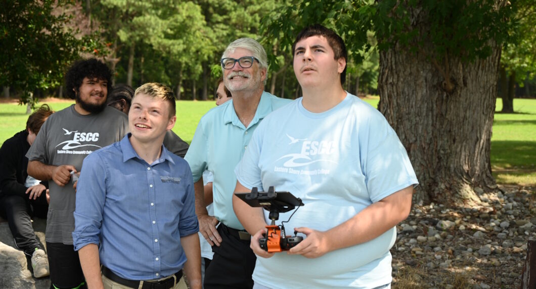 A person controller a drone by remote control while others look on.