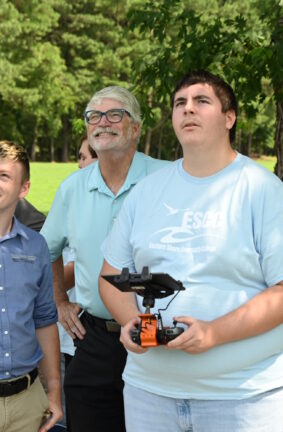 A person controller a drone by remote control while others look on.