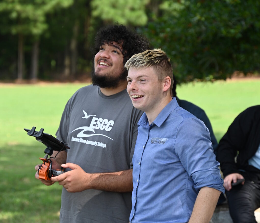 A person using a drone remote control while another person looks on.