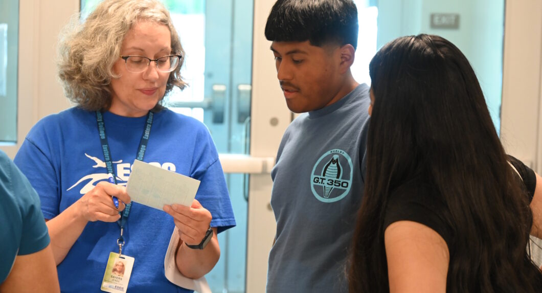 A woman holding an index card and showing it to two people