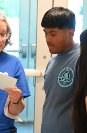 A woman holding an index card and showing it to two people