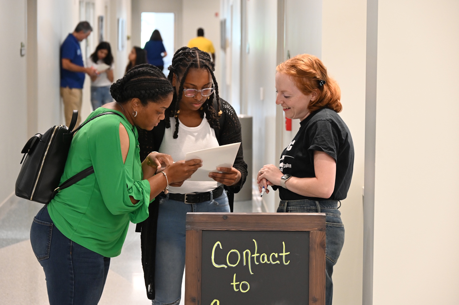 Three women looking at some papers while standing in a hallway