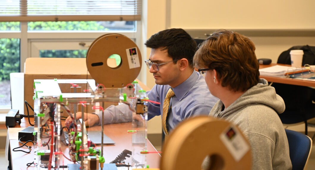 People seated at worktables using equipment