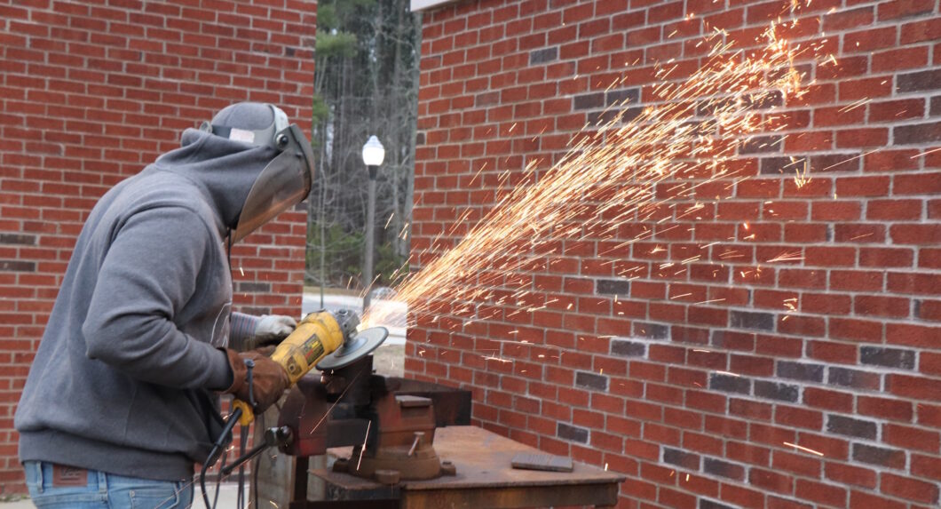 A person wearing protective gear and using an angle grinder