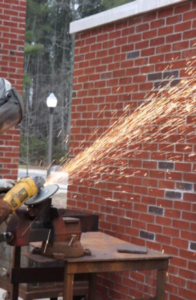 A person wearing protective gear and using an angle grinder