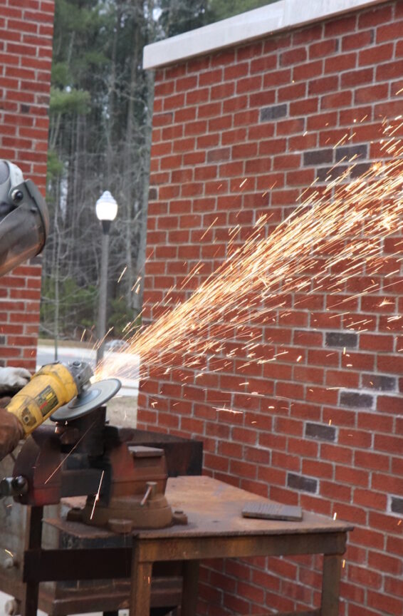 A person wearing protective gear and using an angle grinder