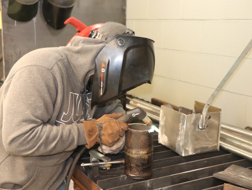 A person wearing protective gear using a blow torch