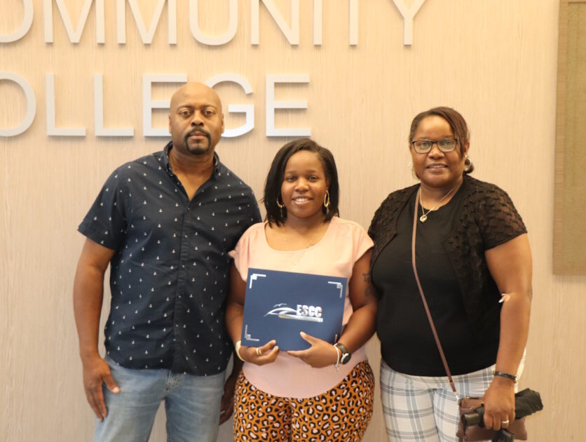 Three people standing in front of a wall with Eastern Shore Community College on it