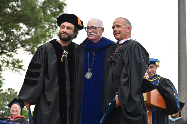Two graduates standing with Dr. Schaeffer