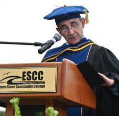A man wearing a cap and gown standing at a podium with a microphone