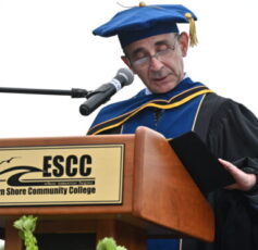 A man wearing a cap and gown standing at a podium with a microphone