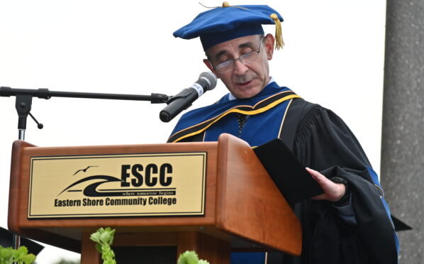 A man wearing a cap and gown standing at a podium with a microphone
