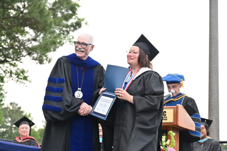 A graduate receiving her diploma from Dr. Schaeffer